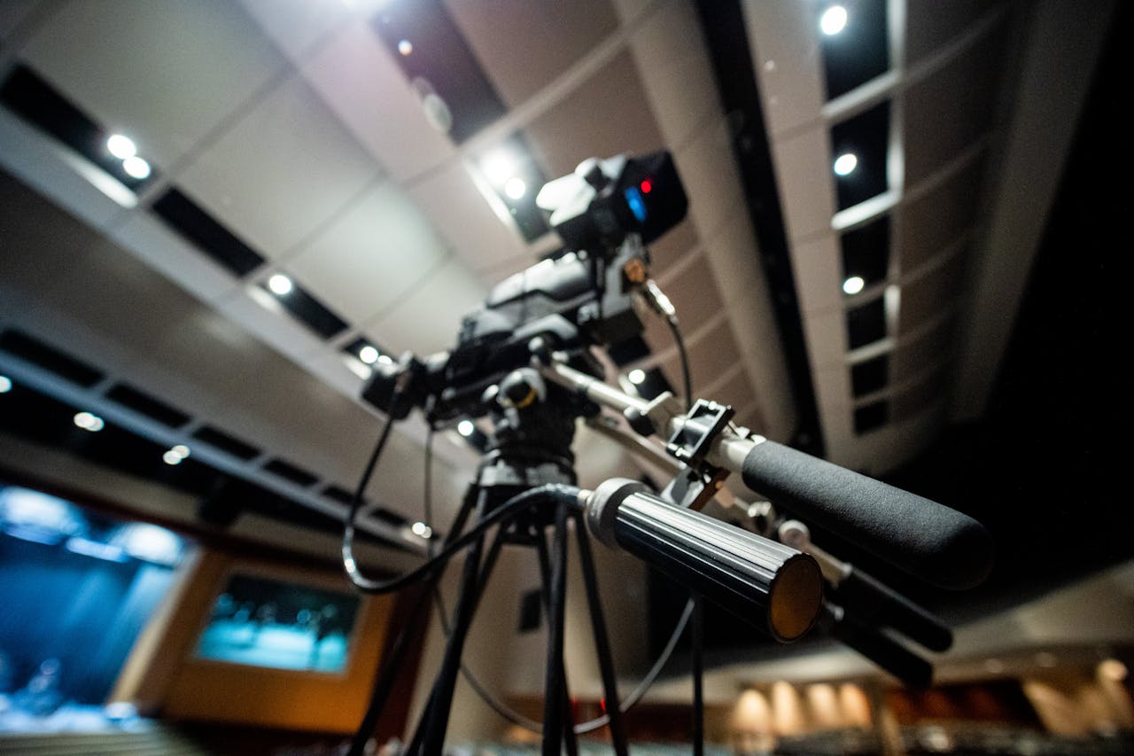 From below of modern professional video camera with wires placed on tripod in studio on blurred background